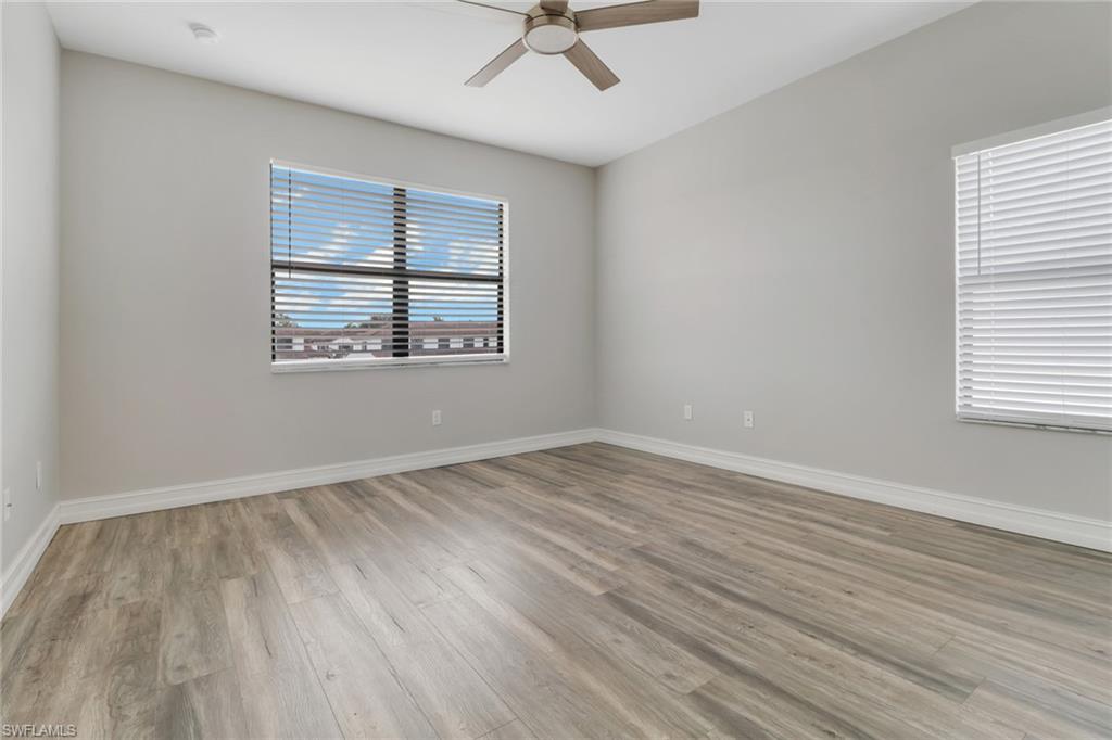7948 Bristol Circle Naples, FL 34120 - Photo 23 of 27 an empty room with wooden floor and windows