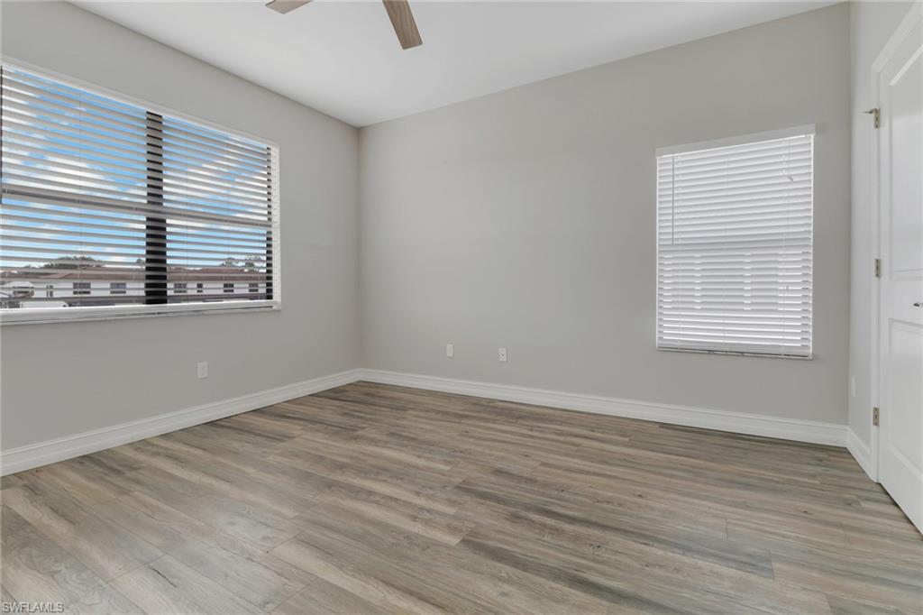 7948 Bristol Circle Naples, FL 34120 - Photo 24 of 27 an empty room with wooden floor and windows