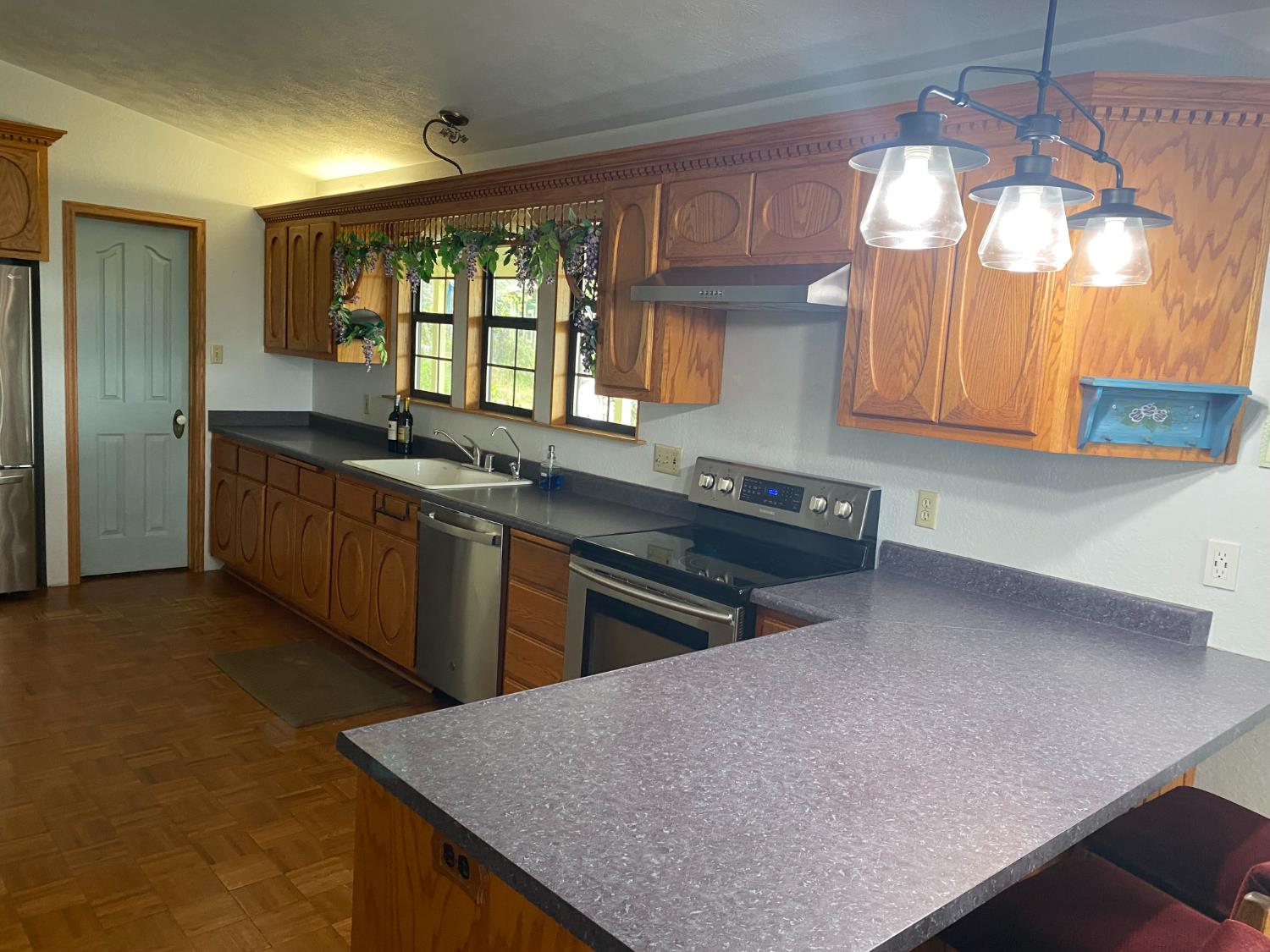5021 Banbury Cross Road Shingle Springs, CA 95682 - Photo 15 of 92 Kitchen view of the L shaped counter and cabinets above and below. Take a good look at the workmanship, the wood tile floor where water might splash. The 3 windows bring in the morning light.