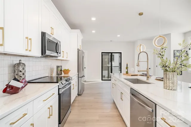 a large kitchen with stainless steel appliances granite countertop a lot of counter space and wooden floors