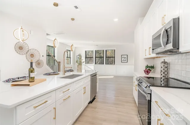 a kitchen with stainless steel appliances granite countertop a sink and cabinets with wooden floor