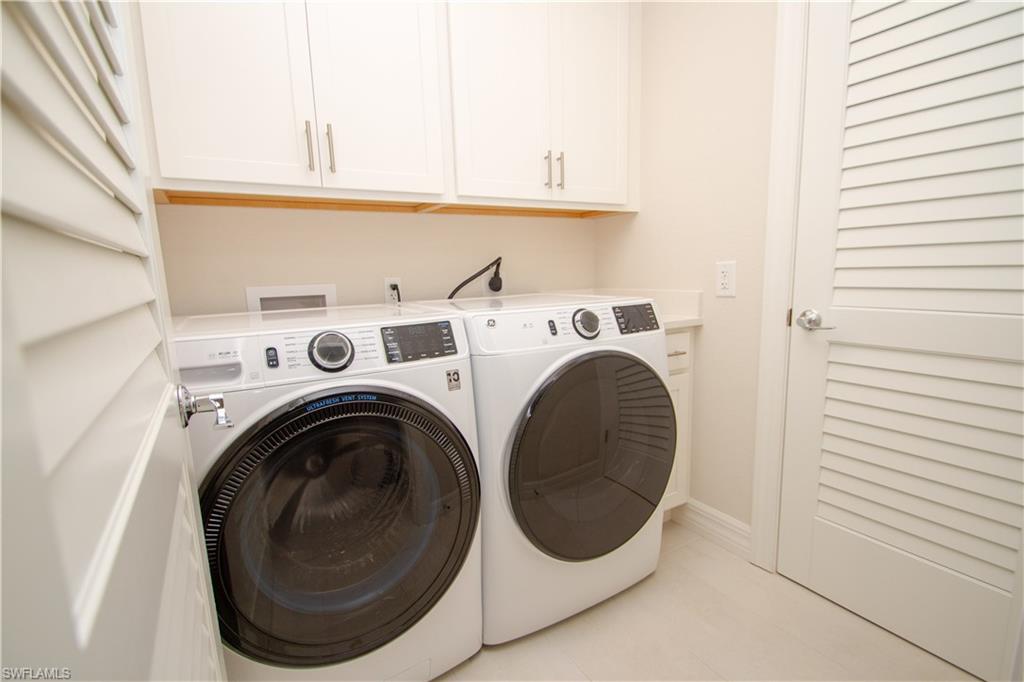 232 Indies Drive East, Unit 101 Naples, FL 34114 - Photo 12 of 50 a view of washer and dryer with kitchen in the background