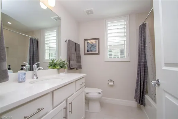 a bathroom with a granite countertop sink toilet and large mirror