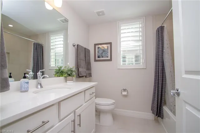 a bathroom with a granite countertop sink toilet and large mirror