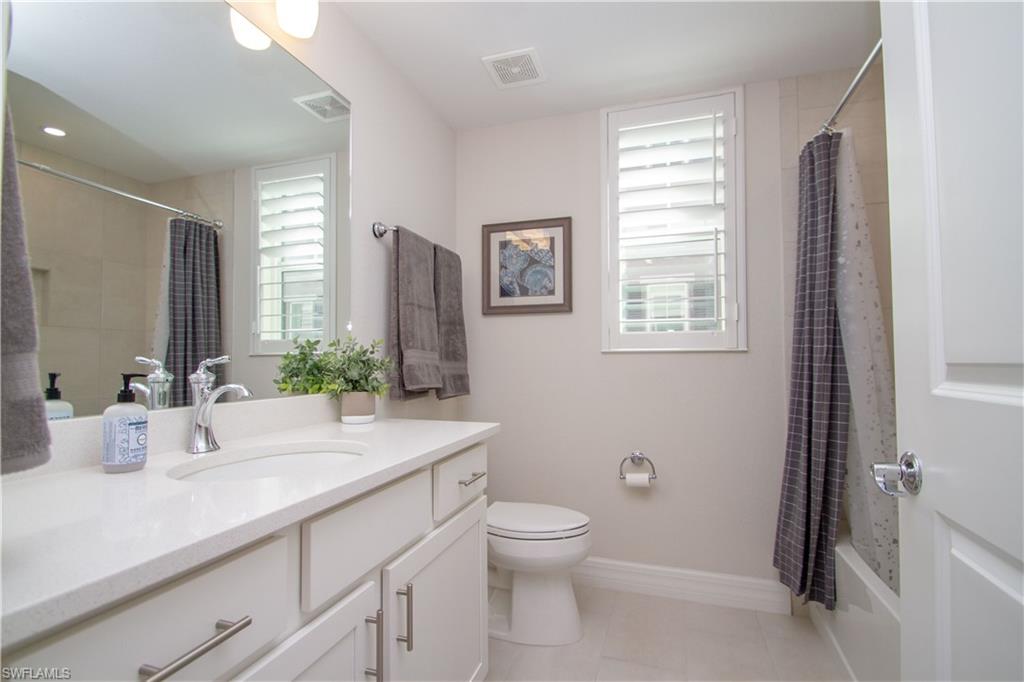 232 Indies Drive East, Unit 101 Naples, FL 34114 - Photo 13 of 50 a bathroom with a granite countertop sink toilet and large mirror