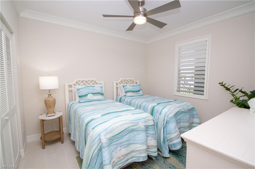 232 Indies Drive East, Unit 101 Naples, FL 34114 - Photo 15 of 50 a bedroom with two beds and a chandelier