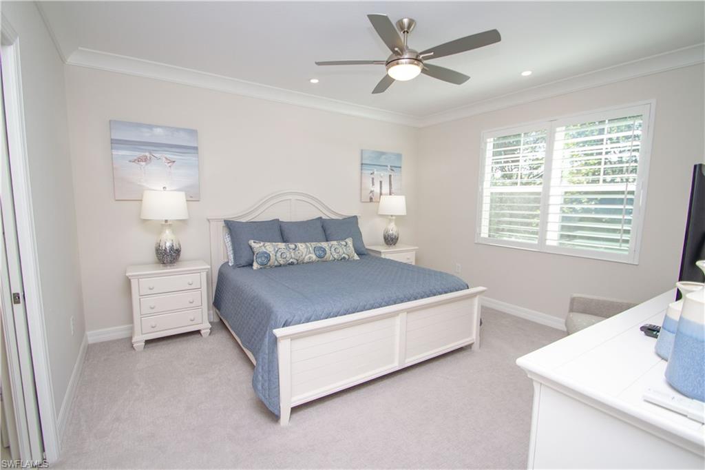 232 Indies Drive East, Unit 101 Naples, FL 34114 - Photo 20 of 50 a spacious bedroom with a bed and a table in it