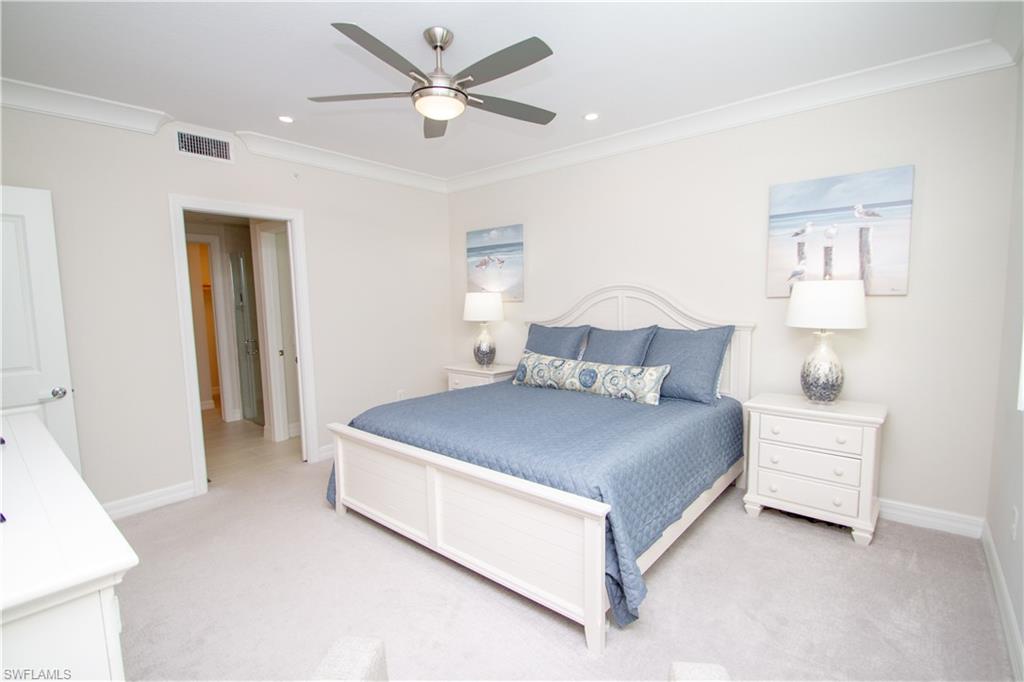 232 Indies Drive East, Unit 101 Naples, FL 34114 - Photo 21 of 50 a bedroom with a bed and a chandelier