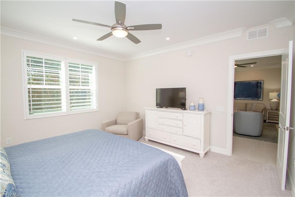 232 Indies Drive East, Unit 101 Naples, FL 34114 - Photo 23 of 50 a bedroom with a bed a flat screen tv and a couch