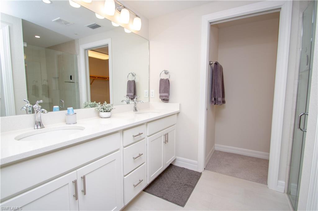 232 Indies Drive East, Unit 101 Naples, FL 34114 - Photo 24 of 50 a bathroom with a double vanity sink and a mirror