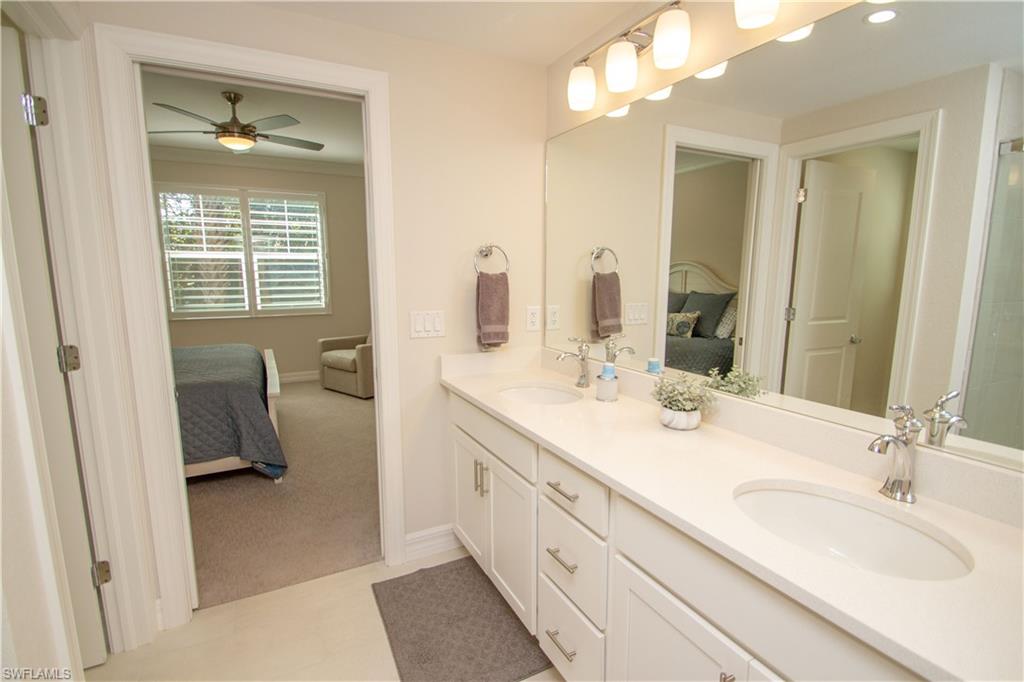 232 Indies Drive East, Unit 101 Naples, FL 34114 - Photo 27 of 50 a en suite bathroom with a double vanity sink a mirror and a shower