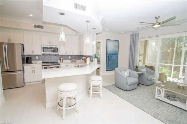 a large kitchen with kitchen island a large counter top space a sink stainless steel appliances and cabinets