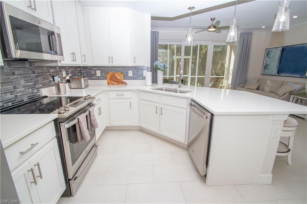 232 Indies Drive East, Unit 101 Naples, FL 34114 - Photo 10 of 50 a kitchen that has a sink and a stove in it