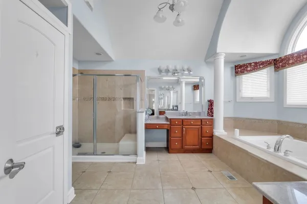 a spacious bathroom with a tub sink shower and mirror