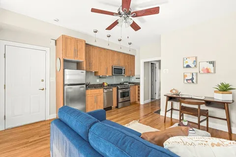 a kitchen with stainless steel appliances granite countertop a refrigerator a sink dishwasher a stove with white cabinets and wooden floor