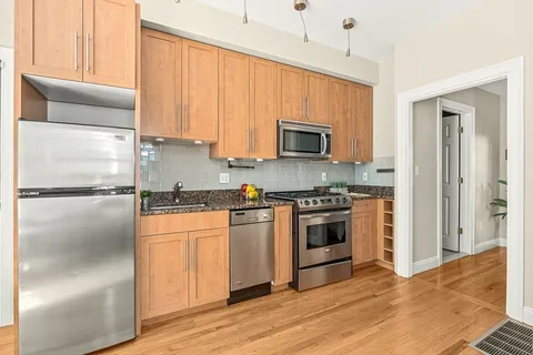 a kitchen with kitchen island granite countertop a stove top oven a sink and a refrigerator