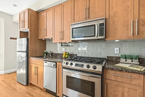 a kitchen with stainless steel appliances granite countertop a stove a microwave and a white cabinets