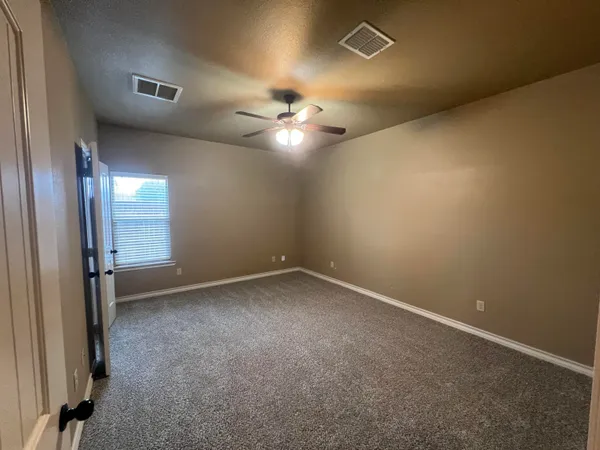 an empty room with a ceiling fan and window