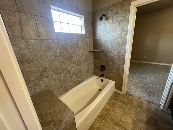 a bathroom with a tub shower and sink