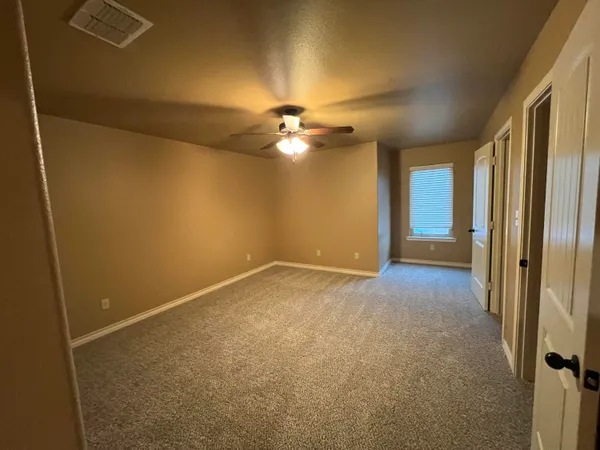 an empty room with a chandelier fan and windows