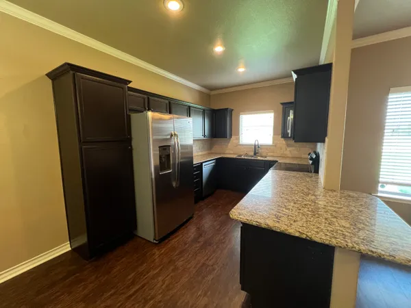 a kitchen with granite countertop kitchen island wooden floors and stainless steel appliances