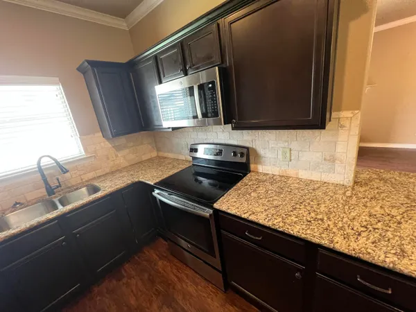 a kitchen with stainless steel appliances granite countertop a sink stove and microwave