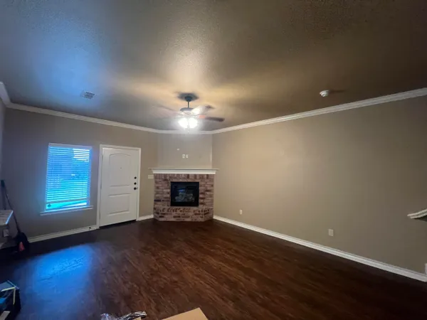 an empty room with wooden floor fireplace and windows