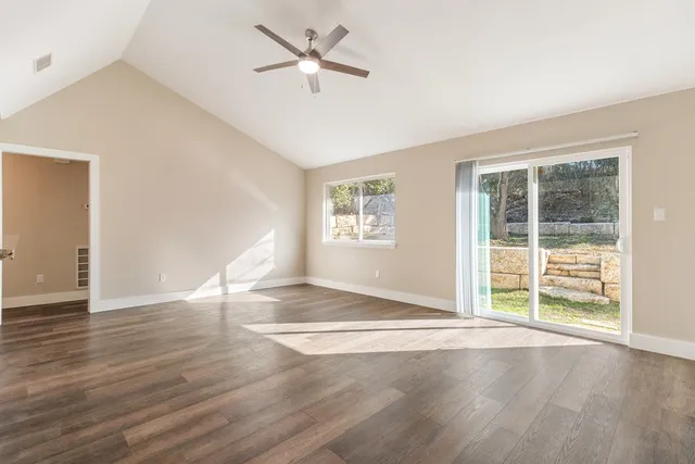 a view of an empty room with a window and wooden floor