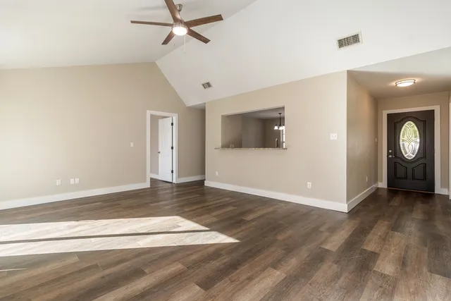 an empty room with wooden floor and windows