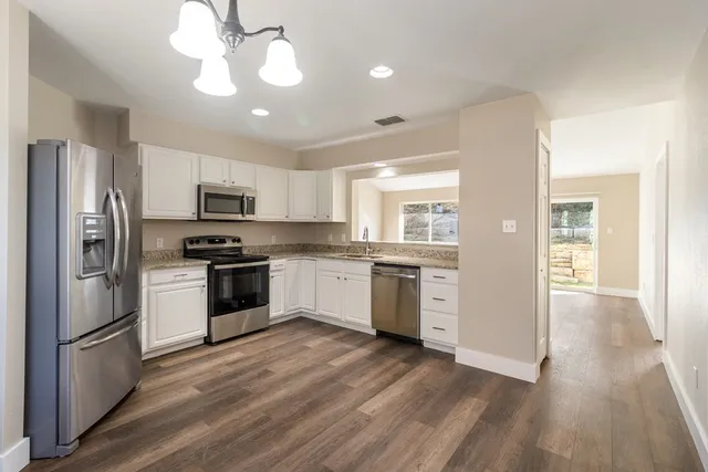 a kitchen with a refrigerator a sink and dishwasher a oven with wooden floor