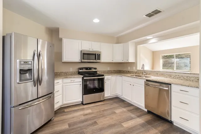a kitchen with granite countertop white cabinets and stainless steel appliances