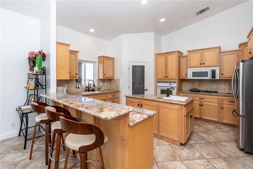 1830 Calaveras Road Pinon Hills, CA 92372 - Photo 9 of 38 a kitchen with stainless steel appliances granite countertop a stove top oven refrigerator a sink dishwasher and cabinets with wooden floor