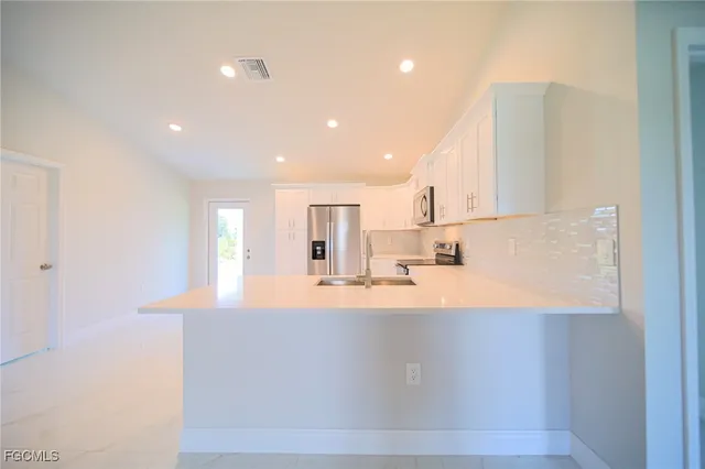 a large white kitchen with kitchen island a sink a stove and a refrigerator