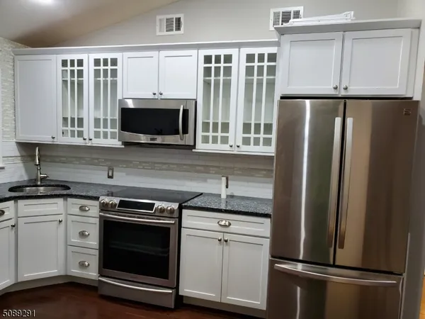 a kitchen with stainless steel appliances white cabinets and a refrigerator