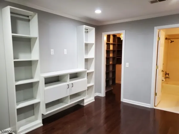 a view of an empty room with wooden floor and closet
