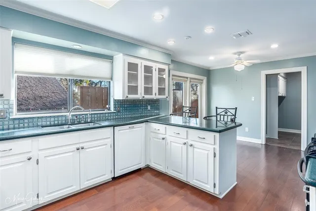 a kitchen with granite countertop white cabinets and a wooden floor