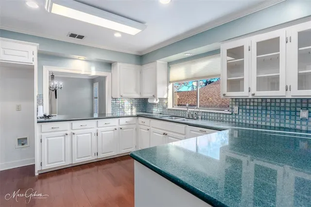 a kitchen with granite countertop a sink and white cabinets