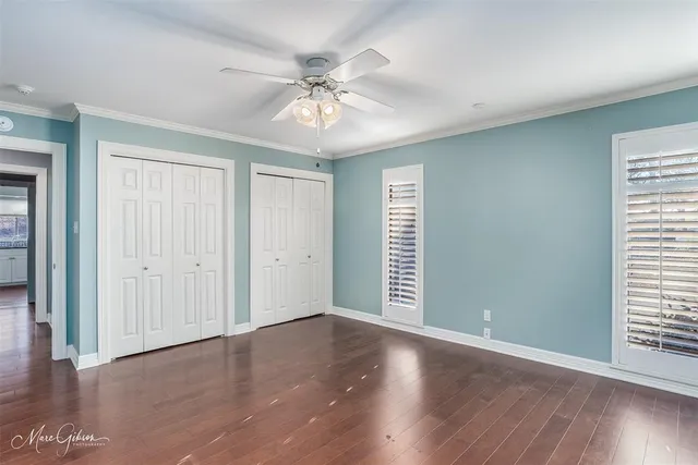 an empty room with wooden floor closet and windows