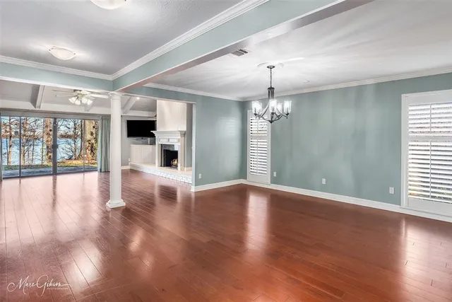 a view of an empty room with wooden floor and a chandelier