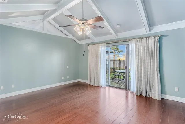 an empty room with wooden floor fan and windows