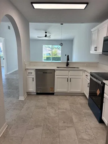 a large white kitchen with a stove a sink and dishwasher