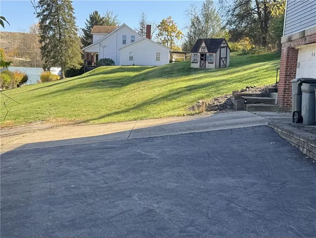 a view of a house with a yard and a large tree