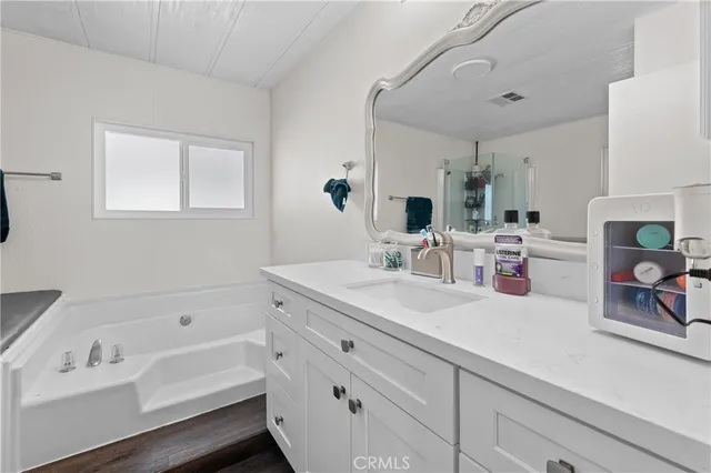 a bathroom with double vanity sink a mirror and a bathtub