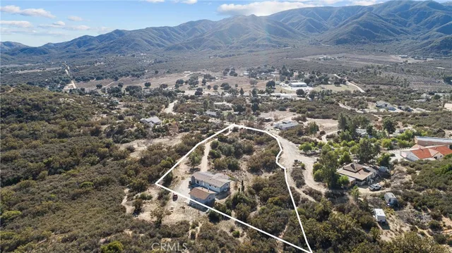 an aerial view of house with yard and mountain view in back