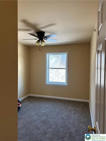 an empty room with a ceiling fan and window