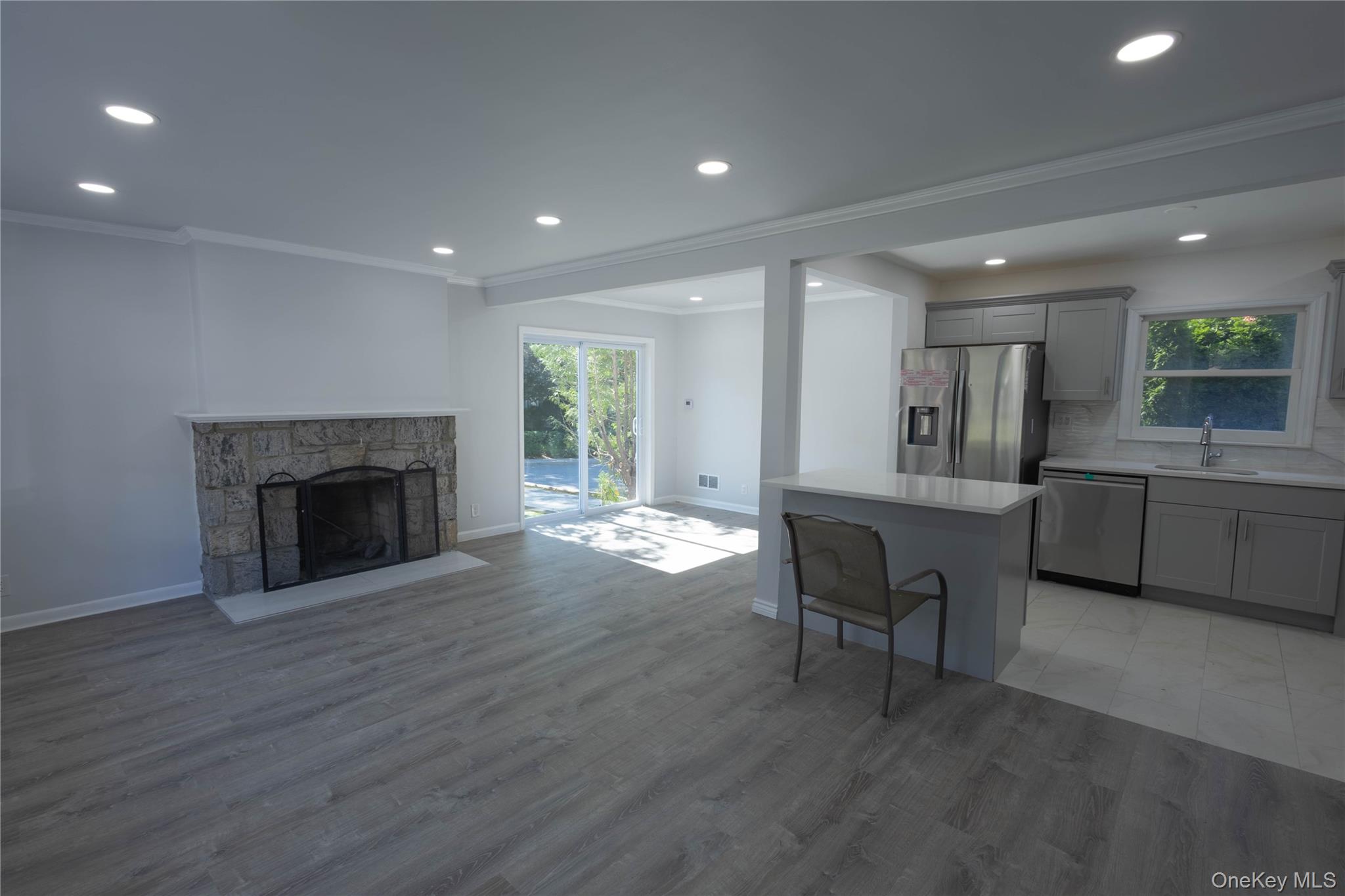 416 Bronxville Road Bronxville, NY 10708 - Photo 1 of 1 Kitchen with gray cabinets, appliances with stainless steel finishes, crown molding, a stone fireplace, and open floor plan