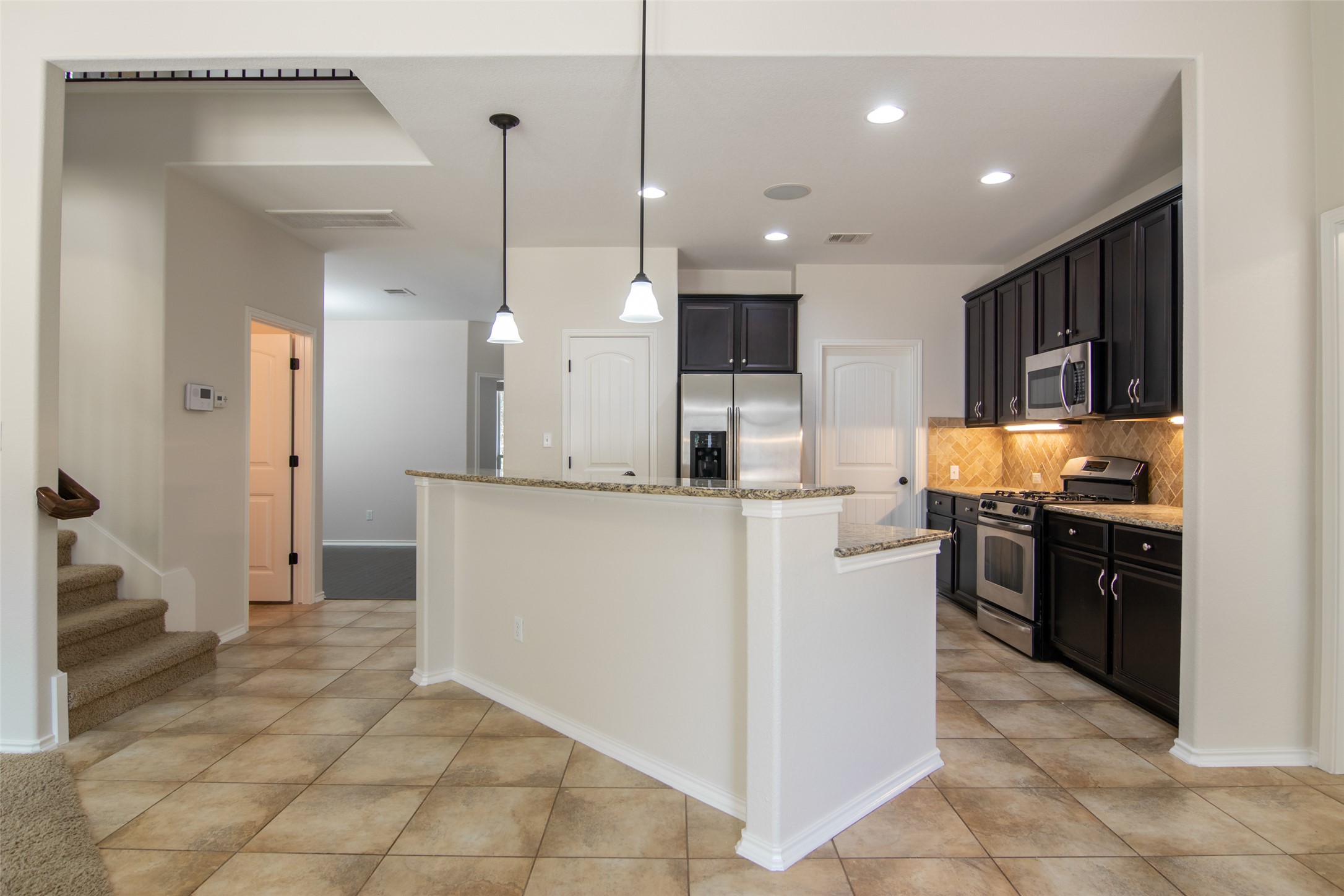 12104 Broten Street Austin, TX 78748 - Photo 7 of 32 A well-appointed kitchen features dark cabinetry, stainless steel appliances, and a convenient breakfast bar.