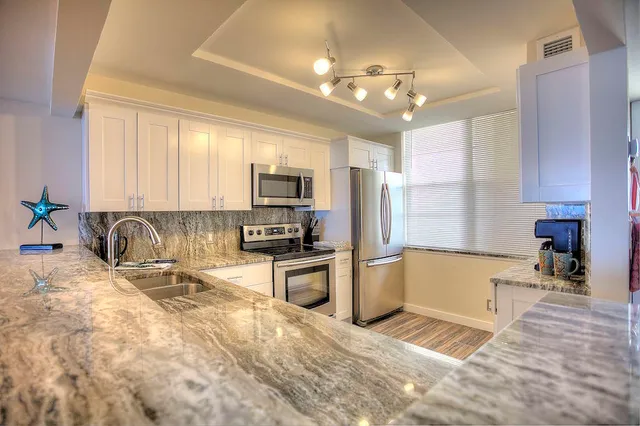 a large kitchen with kitchen island granite countertop a sink counter top space appliances and cabinets