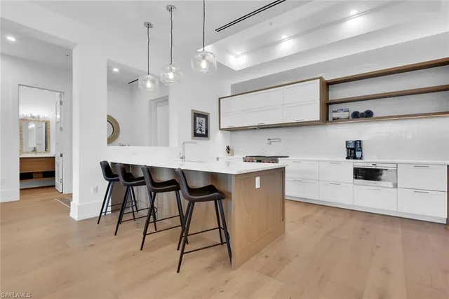 a large white kitchen with lots of counter space a sink appliances and cabinets