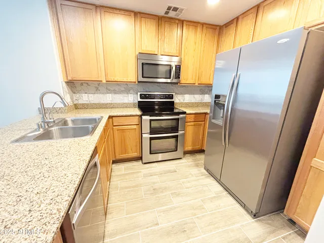 a kitchen with granite countertop a refrigerator and a sink